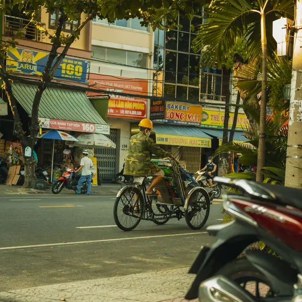 A Da Nang street of shop signs, a cyclo and parked scooters