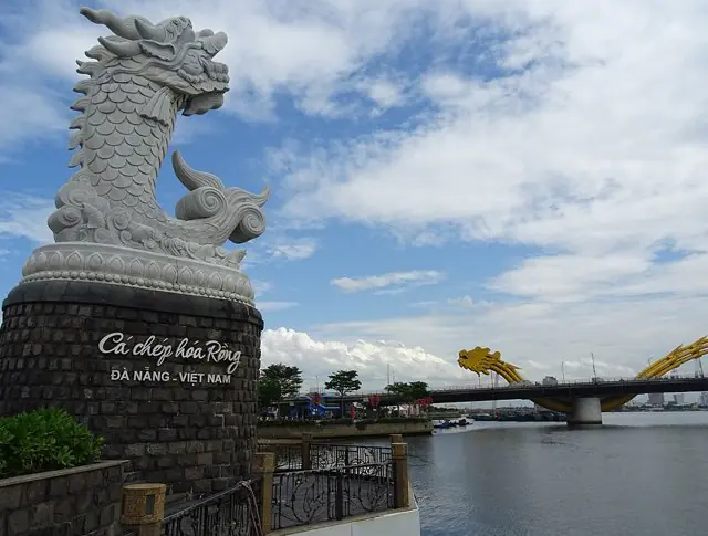 The white marble carp turning into a dragon on the Han River bank, with the yellow Dragon Bridge behind it