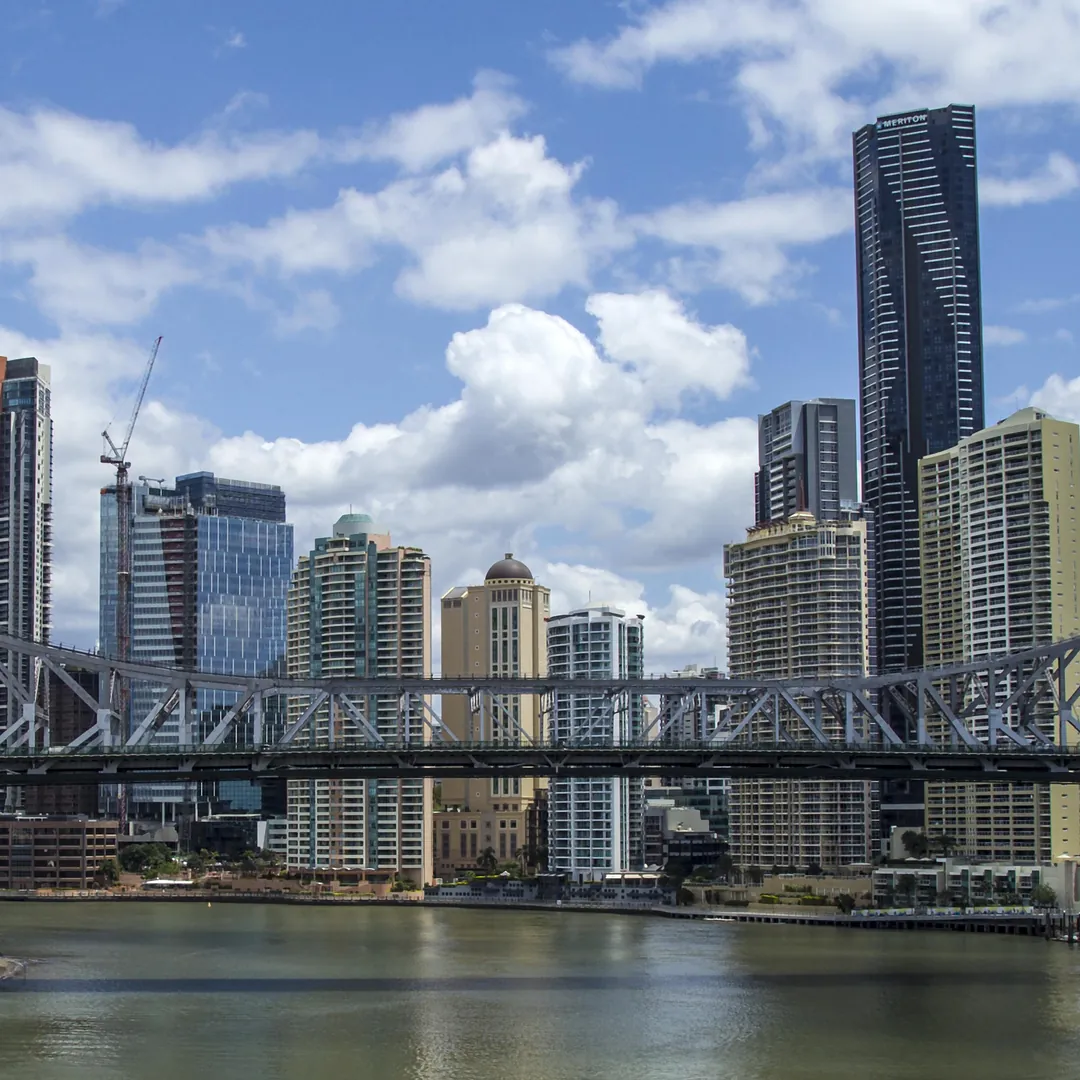 The Story Bridge's grey steel truss across the Brisbane River, with the city towers and white summer cloud behind