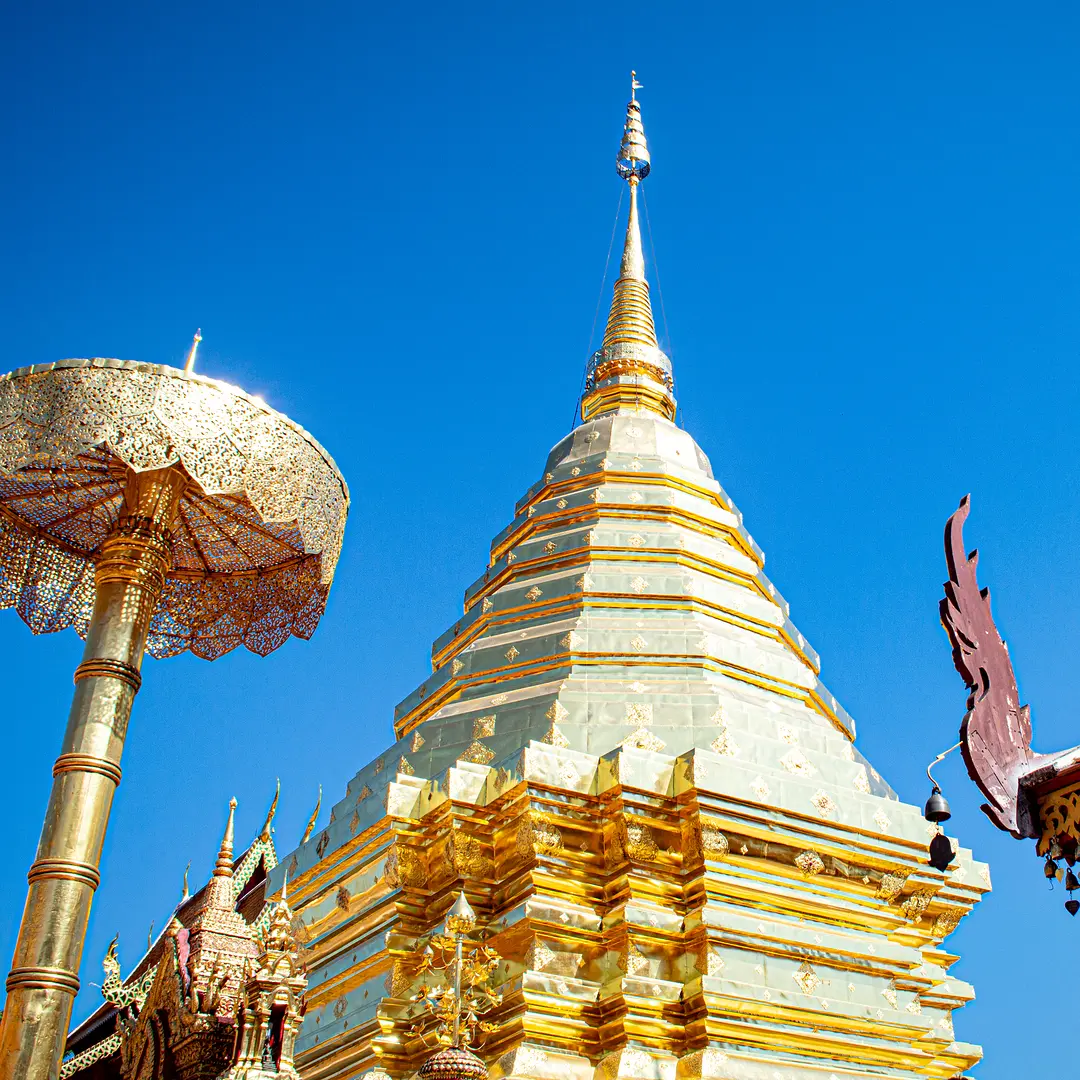 The golden chedi and gold filigree umbrella of Wat Phra That Doi Suthep above Chiang Mai against a deep blue sky